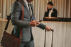 Luxury hotel uniforms. Stylish hotel guest dressed in a suit leaves hotel desk with luggage